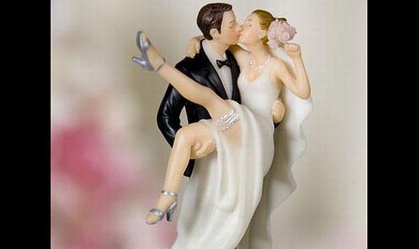 Holding up and kissing wedding cake topper