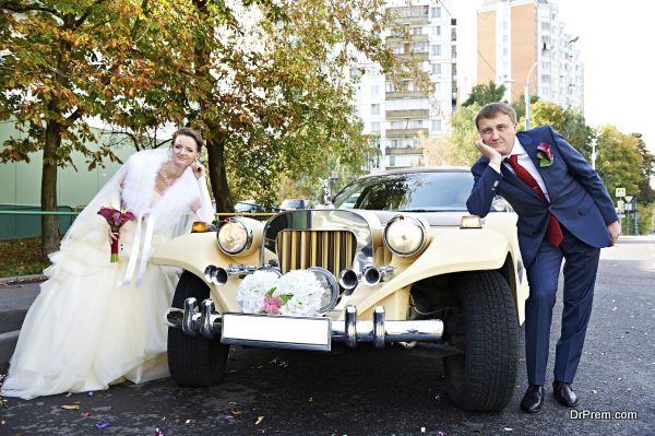 Happy groom and bride about retro limousine