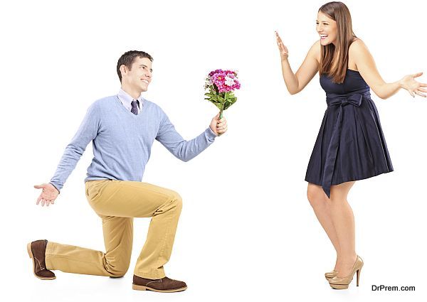 Male kneeling with a bunch of flowers and excited female