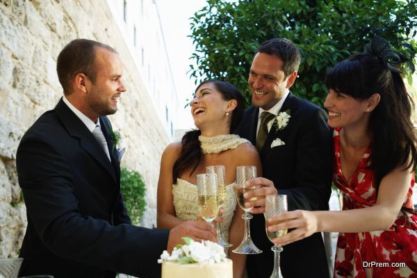 Bride and groom toasting champagne glasses with friends, smiling