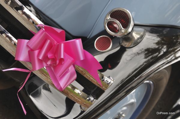 pink ribbon hanging on the back of an old car for a wedding