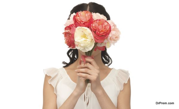 woman holding bouquet of flowers over her face
